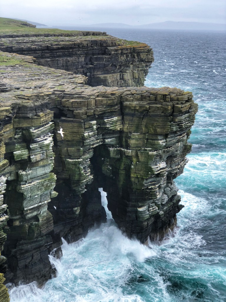 Coastline cliffs with crashing waves below.