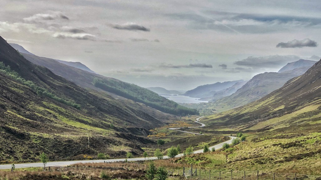 Rural scene of a deep glen with mountains raising up on both sides.