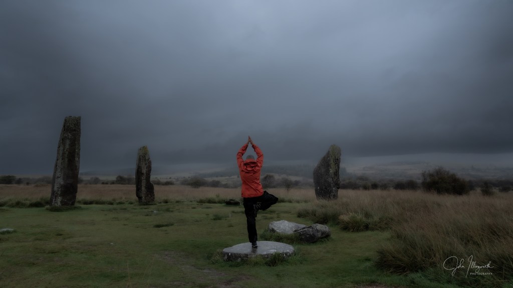 Figure standing in a tree pose amongst a stone circle 