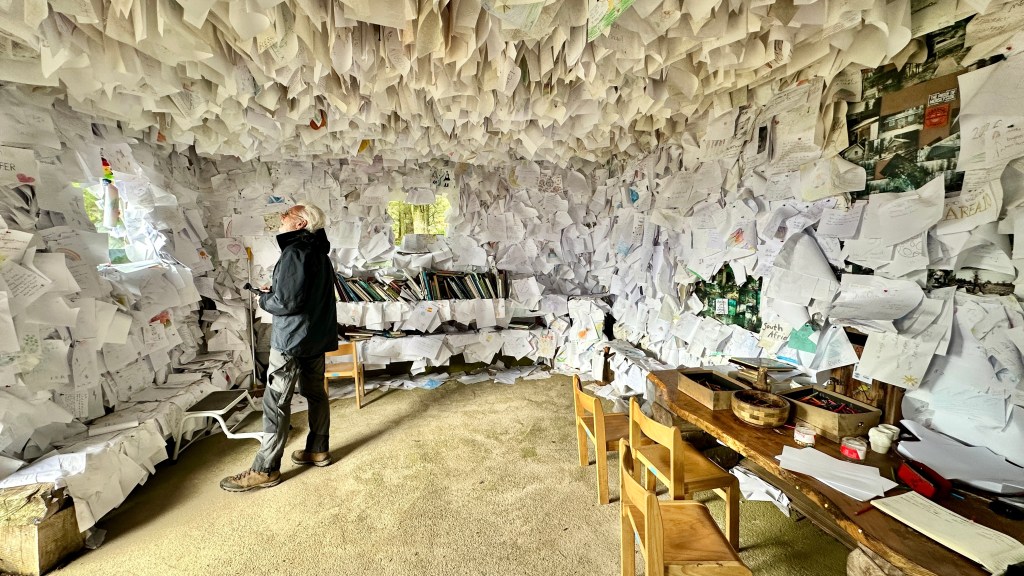 Wooden hut entirely covered in pieces of paper hanging from the walls and ceiling